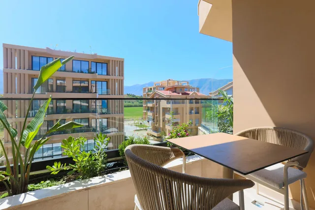 Balcony with a table and chairs, greenery and mountains beyond