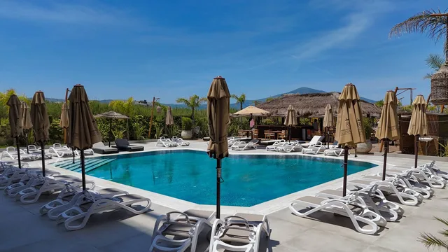 Pool with sun loungers, mountains beyond