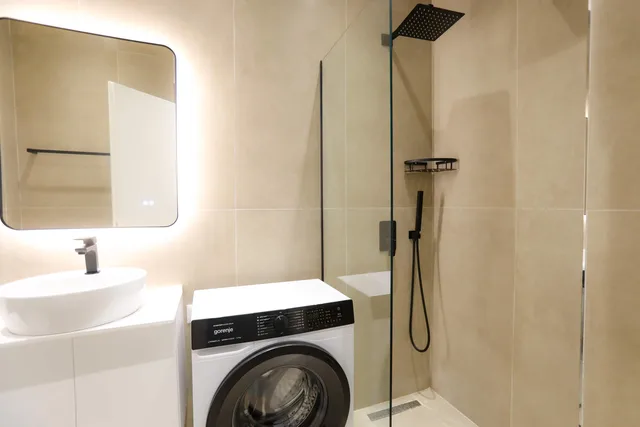Bathroom with shower, basin and washing machine